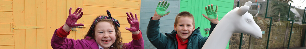 Kids with painted hands next to a giraffe sculpture