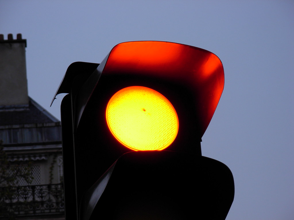 A red traffic light shines at dusk